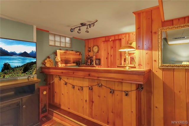 bar featuring a bar, track lighting, and wood walls