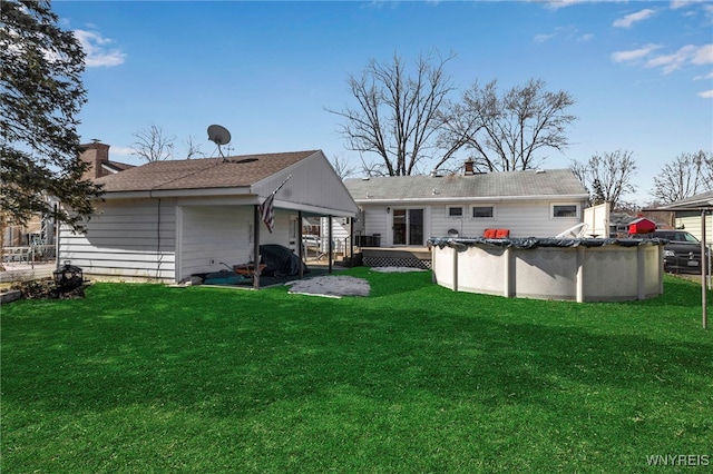 back of property featuring a covered pool, a lawn, and a chimney