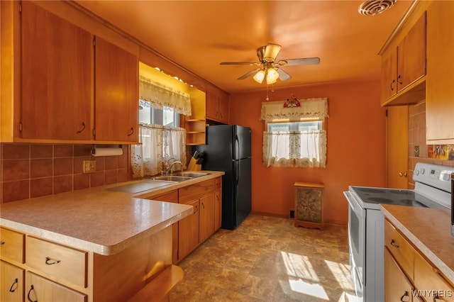 kitchen with visible vents, white range with electric cooktop, freestanding refrigerator, a sink, and tasteful backsplash