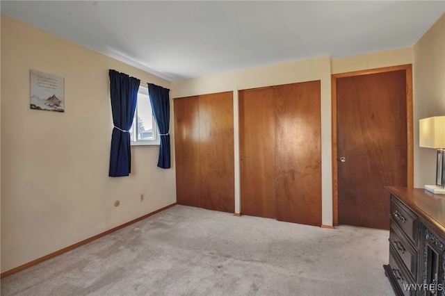 unfurnished bedroom with baseboards, multiple closets, and carpet floors