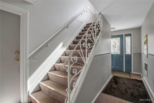 stairway featuring a baseboard heating unit, carpet flooring, and baseboards