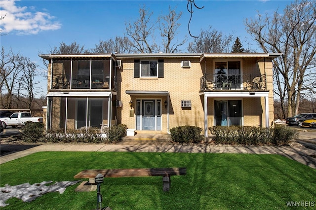 view of front of house featuring brick siding, a front lawn, and a balcony