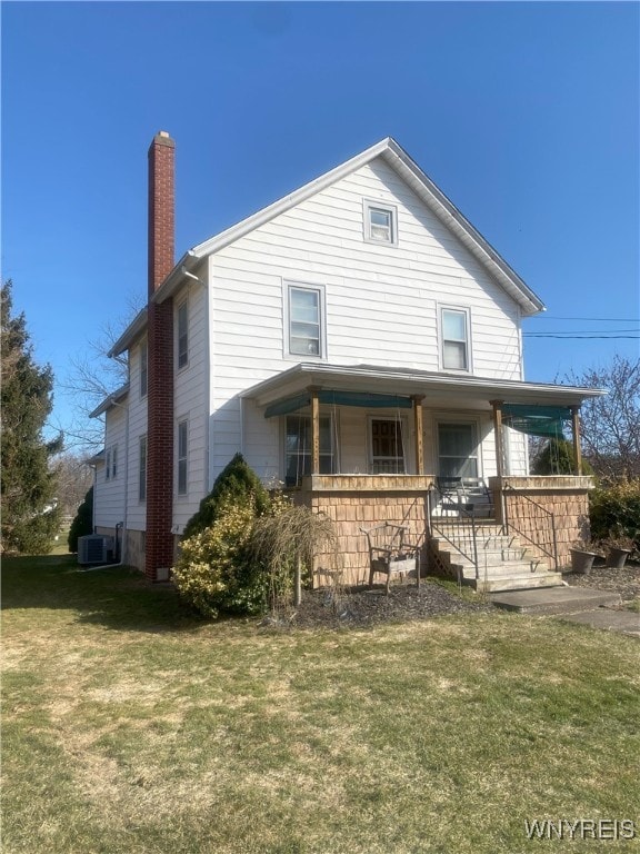 rear view of house with a porch, cooling unit, a lawn, and a chimney