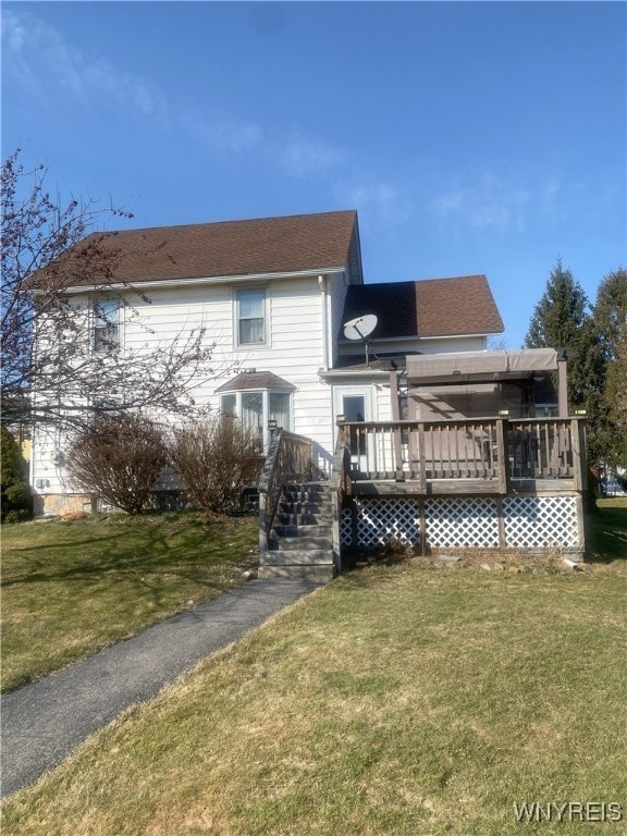 rear view of house featuring a deck and a yard