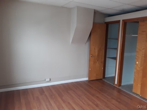 spare room with a paneled ceiling, baseboards, and wood finished floors