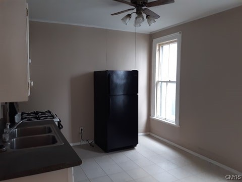 kitchen featuring a sink, plenty of natural light, white cabinetry, and freestanding refrigerator