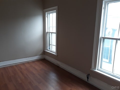 unfurnished room with dark wood-style floors, baseboards, and a wealth of natural light