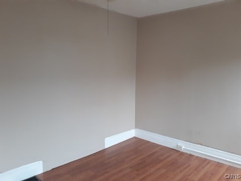 empty room featuring baseboards, attic access, and wood finished floors