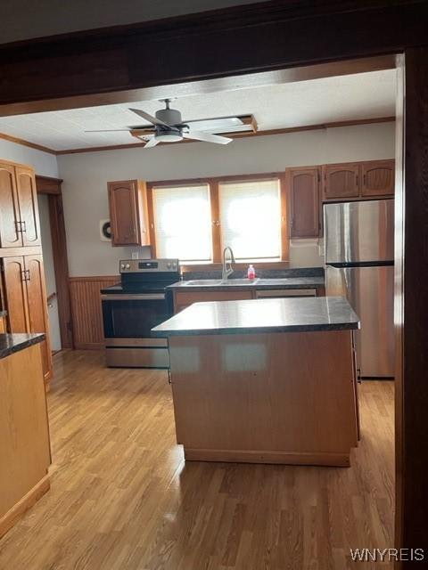 kitchen with dark countertops, light wood finished floors, appliances with stainless steel finishes, and a sink