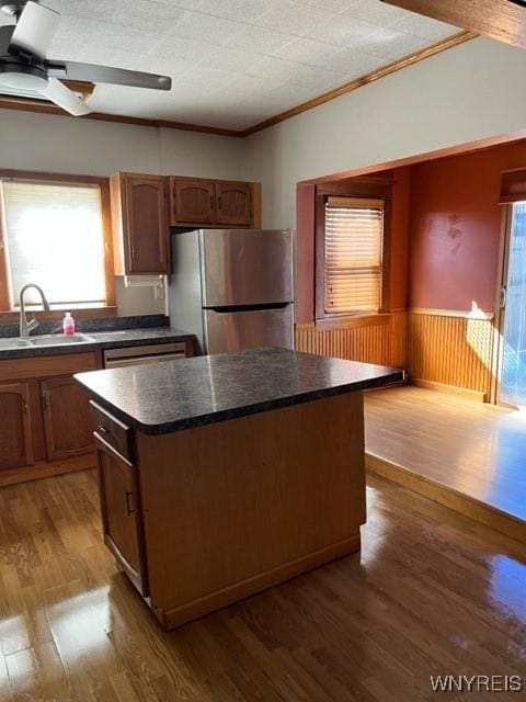 kitchen featuring dark wood-style floors, a kitchen island, a sink, appliances with stainless steel finishes, and dark countertops