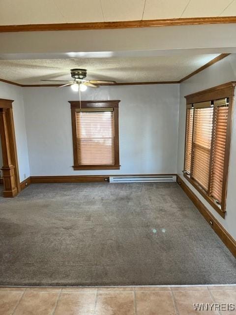 carpeted spare room with crown molding, baseboards, ceiling fan, baseboard heating, and a textured ceiling