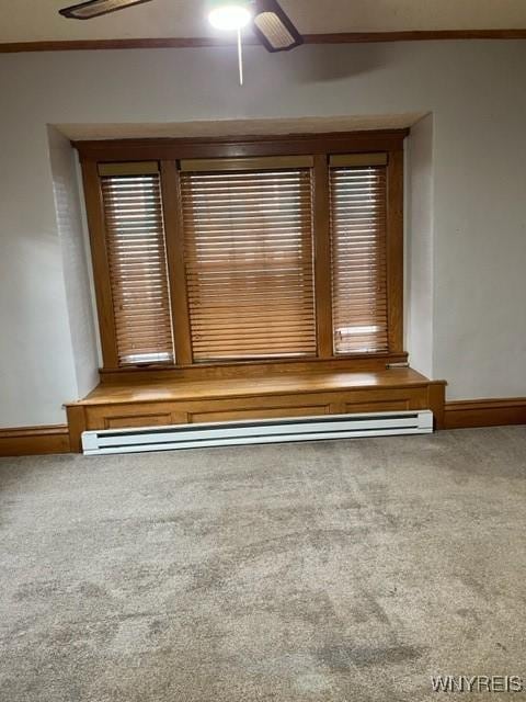 spare room with crown molding, baseboards, carpet floors, and a baseboard radiator