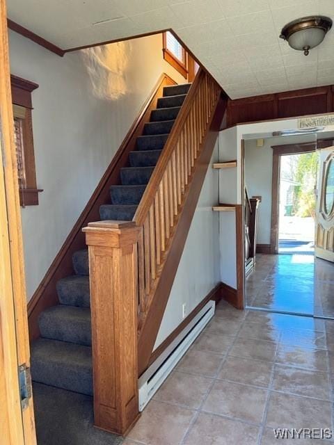 stairs featuring a baseboard heating unit, baseboards, and ornamental molding