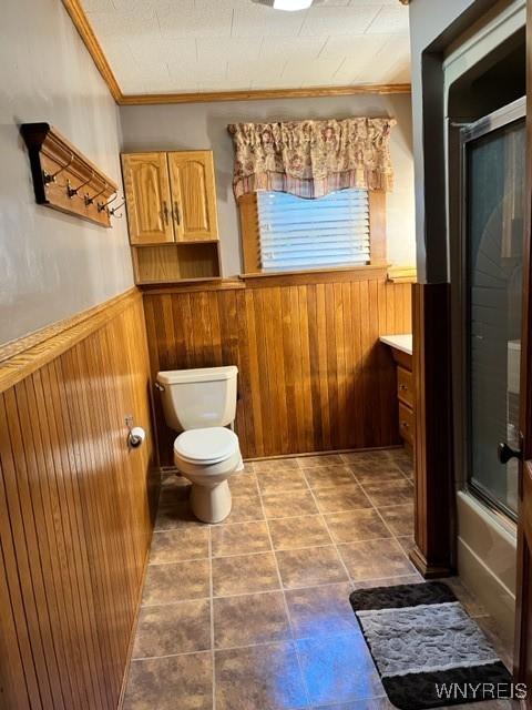 bathroom featuring a wainscoted wall, toilet, wood walls, and crown molding