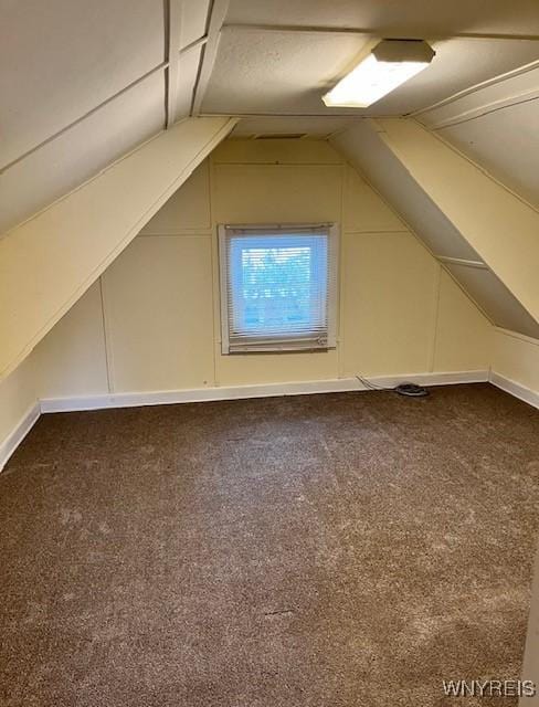 bonus room with dark colored carpet and lofted ceiling