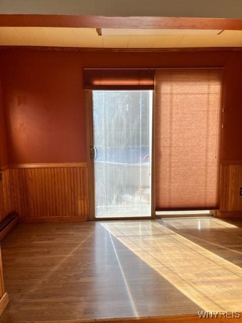 interior space with a wainscoted wall, wood walls, and wood finished floors