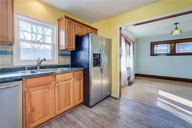 kitchen with dark countertops, decorative backsplash, appliances with stainless steel finishes, and a sink