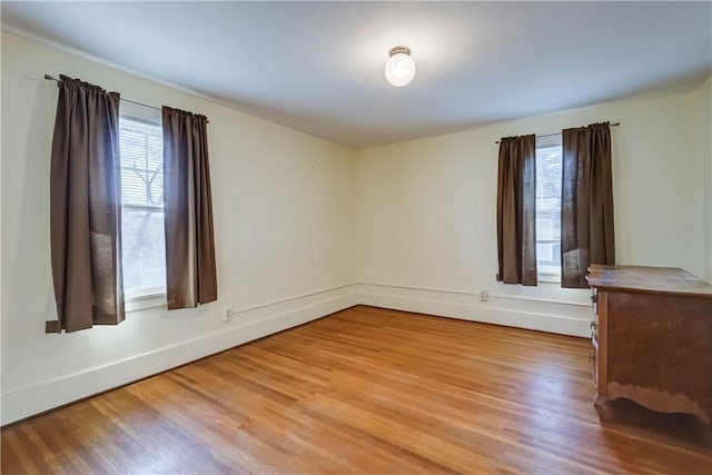 spare room with baseboards and wood finished floors