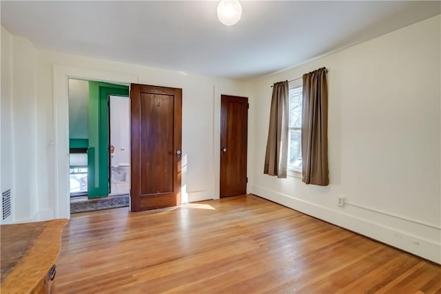 unfurnished bedroom featuring baseboards, visible vents, and light wood finished floors