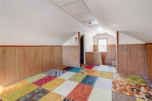 bonus room with lofted ceiling, wooden walls, and wainscoting