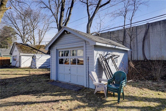 detached garage featuring driveway and fence