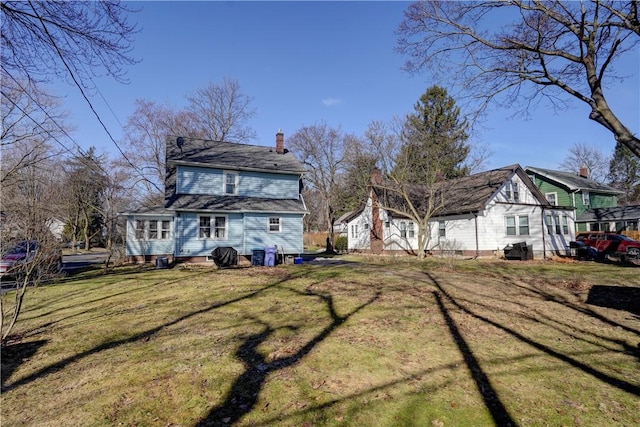 back of property with a chimney and a yard