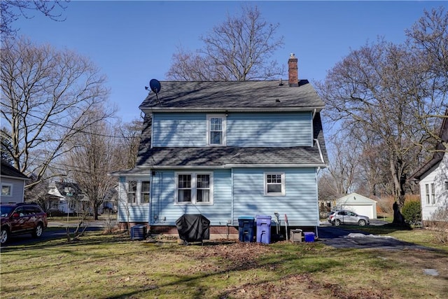 rear view of property featuring a yard, central AC, and a chimney