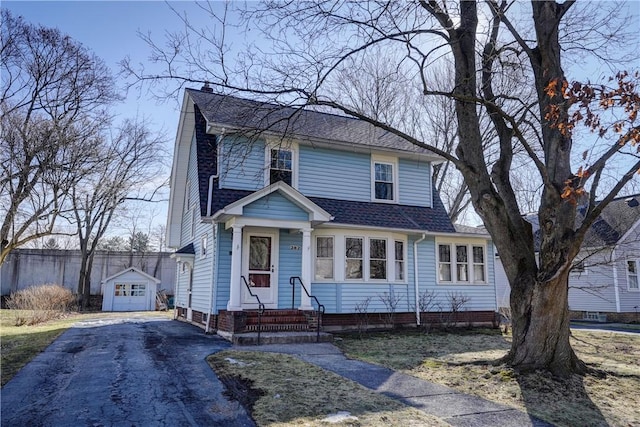 view of front of property with an outbuilding, driveway, roof with shingles, a chimney, and entry steps