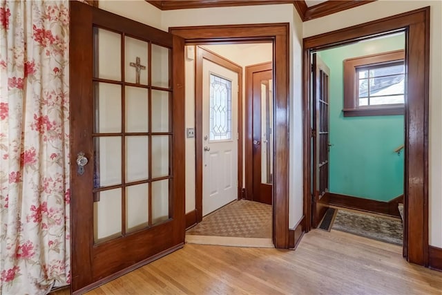 doorway to outside with light wood-style flooring, visible vents, and baseboards