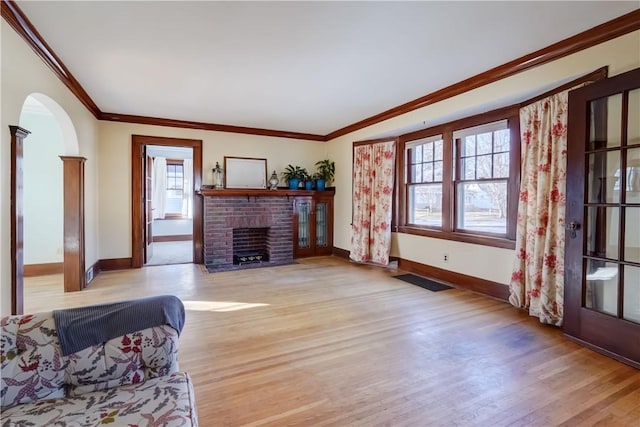 living area featuring baseboards, light wood-style floors, a fireplace, and crown molding