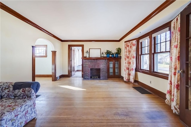 living area featuring arched walkways, visible vents, ornamental molding, and wood finished floors