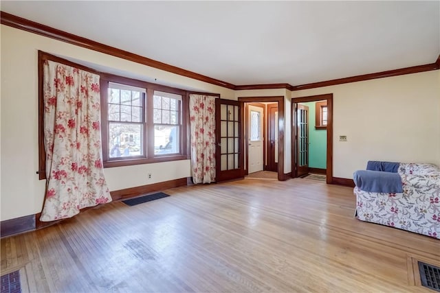 interior space featuring light wood-type flooring, visible vents, baseboards, and crown molding