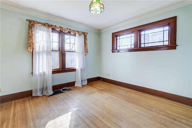 empty room with a wealth of natural light, baseboards, wood finished floors, and crown molding