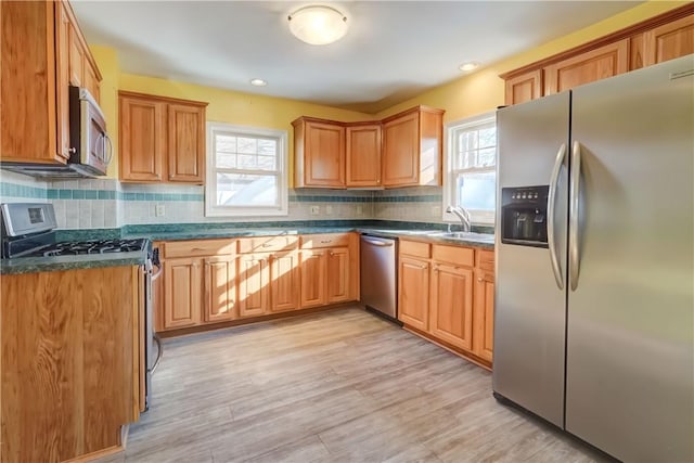 kitchen featuring dark countertops, a healthy amount of sunlight, appliances with stainless steel finishes, and a sink