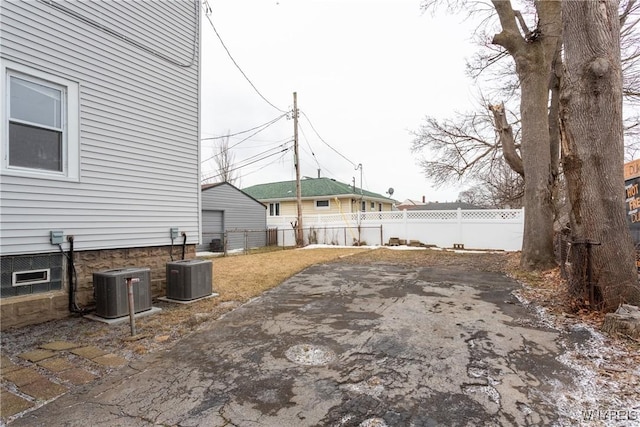 exterior space featuring a fenced backyard, a patio area, a detached garage, and central AC