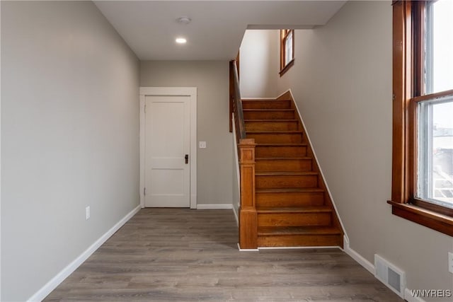 stairway with recessed lighting, visible vents, baseboards, and wood finished floors