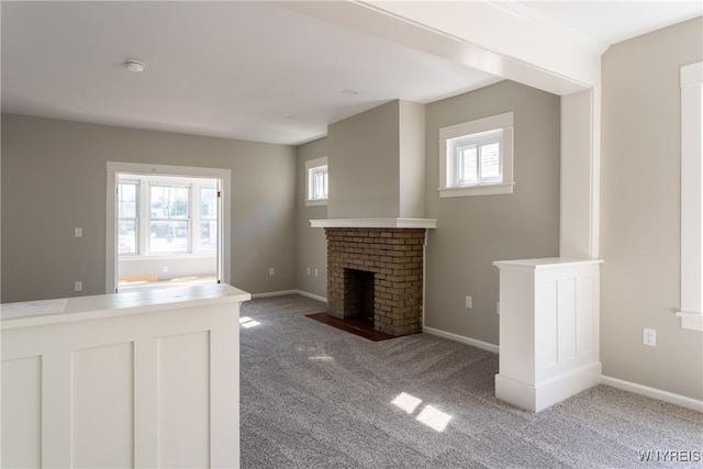 unfurnished living room with baseboards, carpet floors, a healthy amount of sunlight, and a fireplace