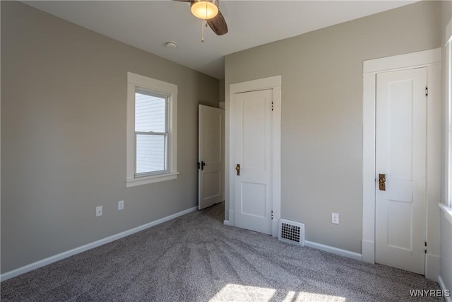 unfurnished bedroom featuring visible vents, two closets, baseboards, and carpet