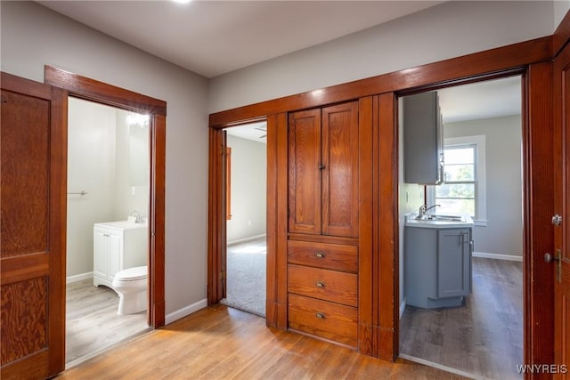 corridor with a sink, baseboards, and light wood-style floors