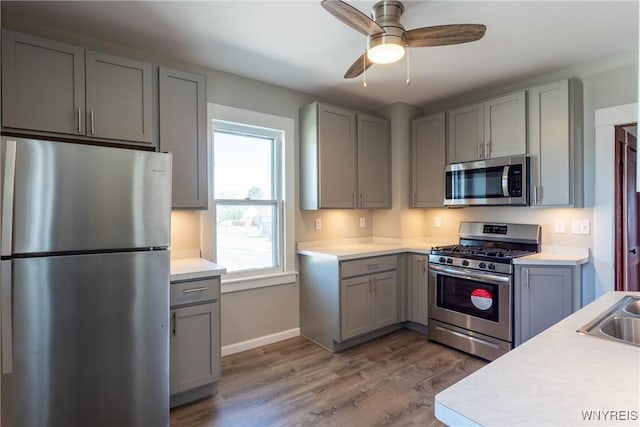 kitchen featuring light countertops, gray cabinetry, light wood-type flooring, and stainless steel appliances