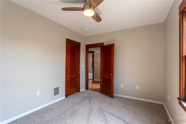 carpeted spare room featuring visible vents, ceiling fan, and baseboards