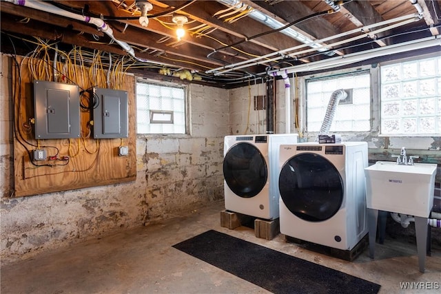 clothes washing area featuring electric panel, laundry area, washer and dryer, and a sink