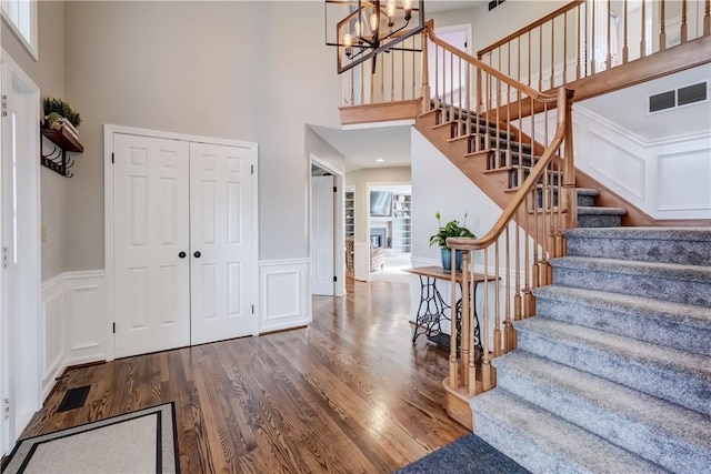 entrance foyer featuring visible vents, stairway, a decorative wall, and wood finished floors