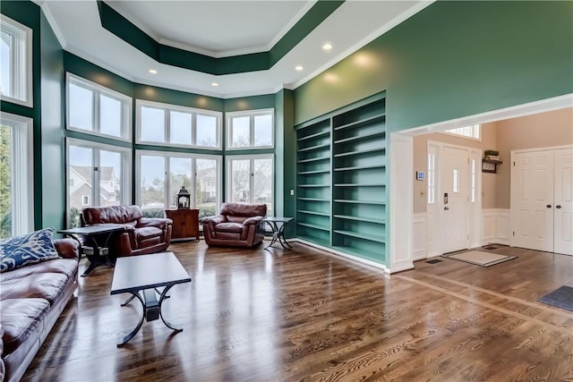 living room with ornamental molding, a towering ceiling, and wood finished floors