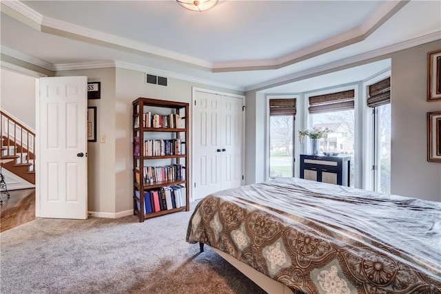 bedroom featuring carpet, baseboards, visible vents, a tray ceiling, and ornamental molding