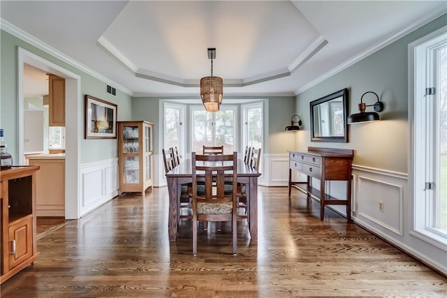 dining area with a tray ceiling, visible vents, dark wood-type flooring, and wainscoting