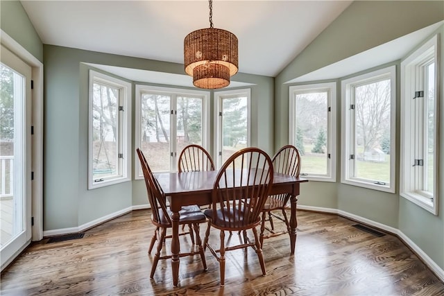 dining room featuring visible vents, lofted ceiling, baseboards, and wood finished floors