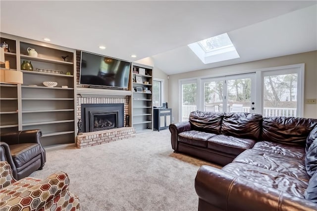 living area featuring vaulted ceiling with skylight, plenty of natural light, a fireplace, and carpet floors