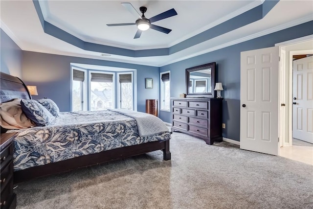 bedroom with ceiling fan, baseboards, a tray ceiling, ornamental molding, and carpet flooring