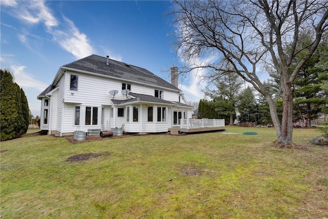 rear view of house with a wooden deck, a lawn, and a chimney